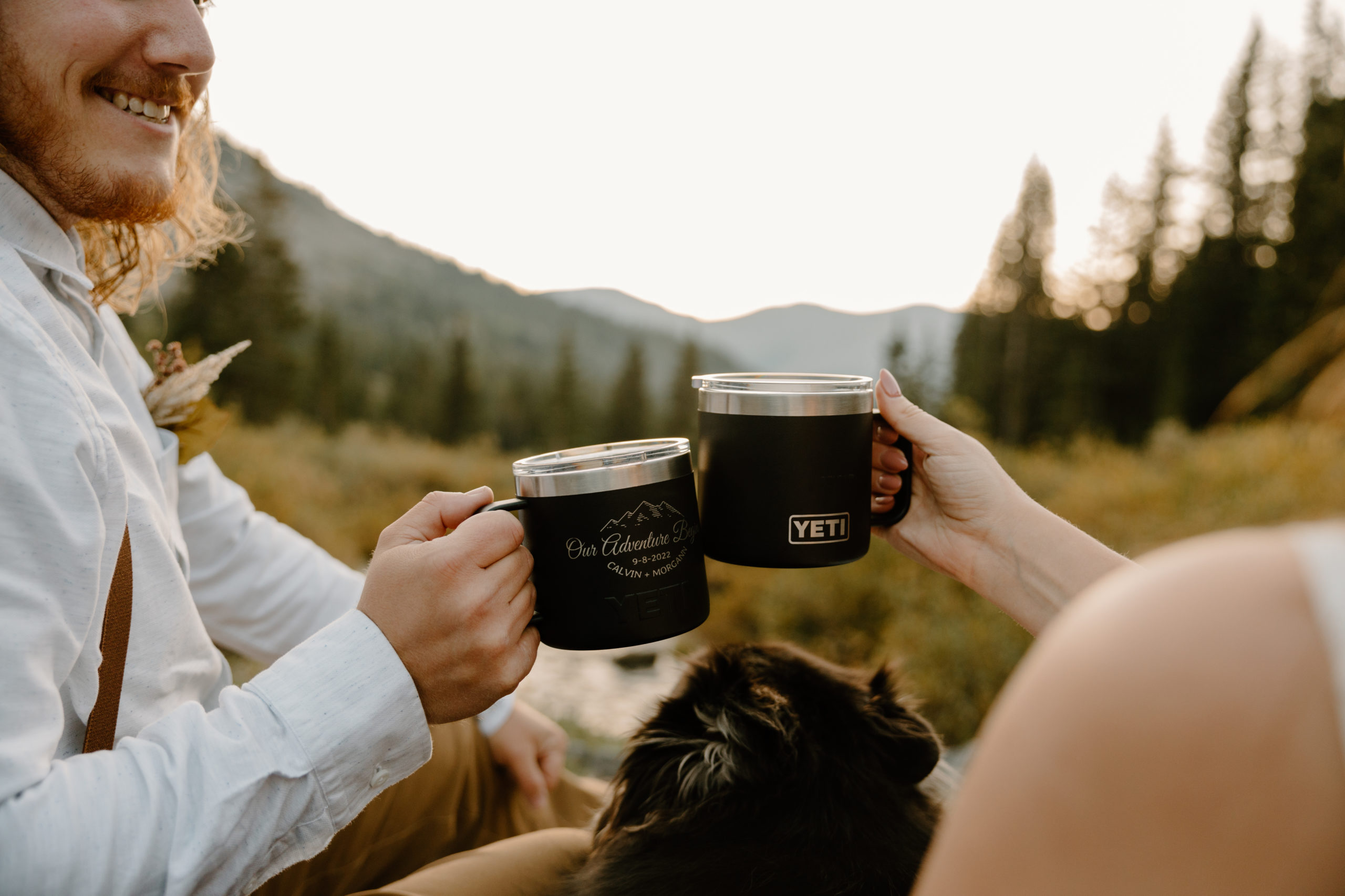 Couple cheers with Yeti mugs while hiking during their adventurous Colorado elopement.