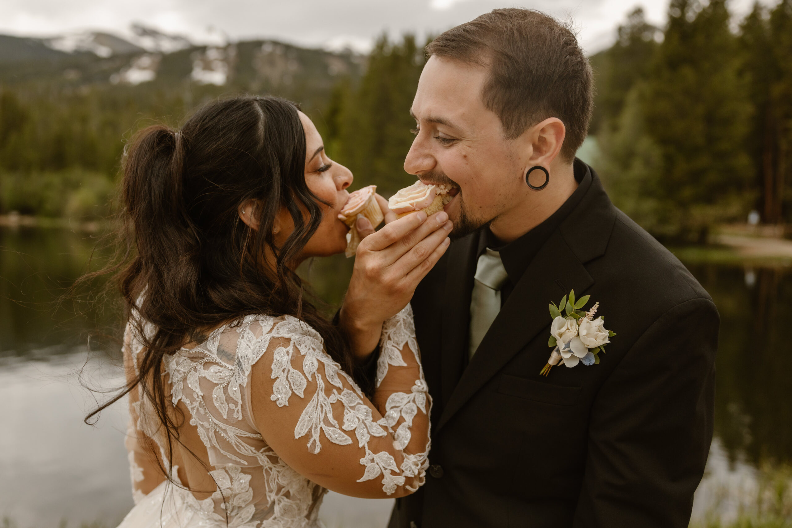 A Bride and groom feed each other cupcakes after their elopement ceremony in the Colorado mountains.
