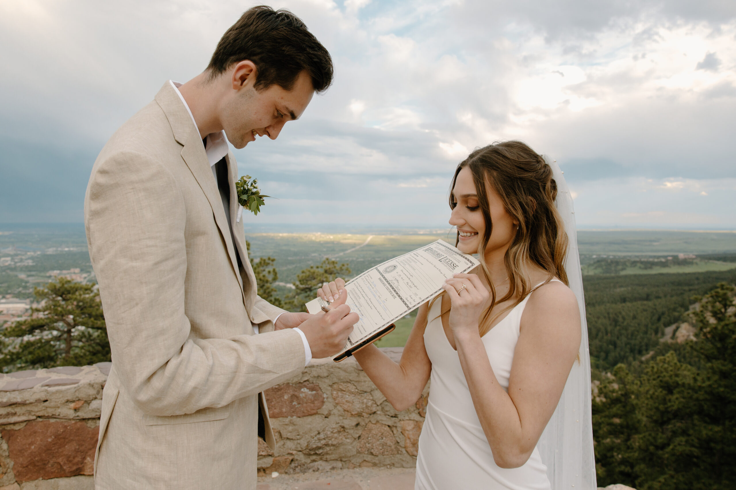 A groom and bride sign their marriage license at Sunrise Amphitheater, one of the best elopement locations in Boulder.