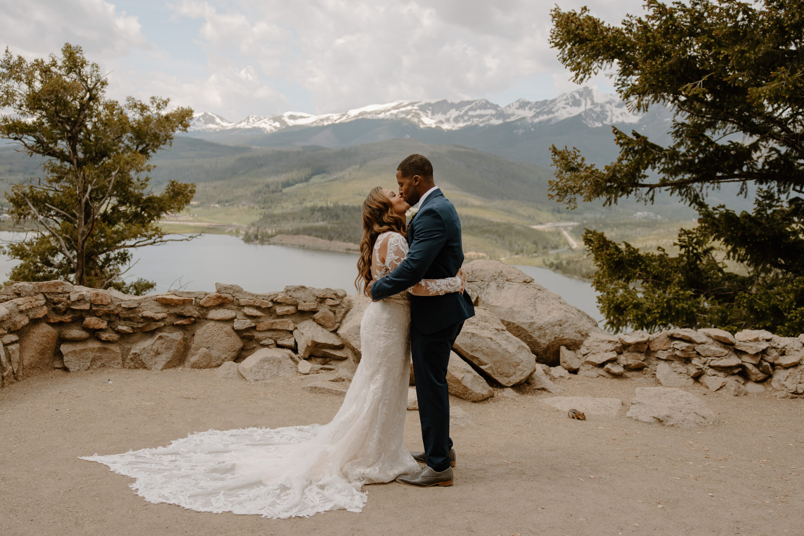 Sapphire Point Overlook is a popular Breckenridge elopement location, and this bride and groom pictures, share their first kiss at the overlook with a chipmunk behind them.
