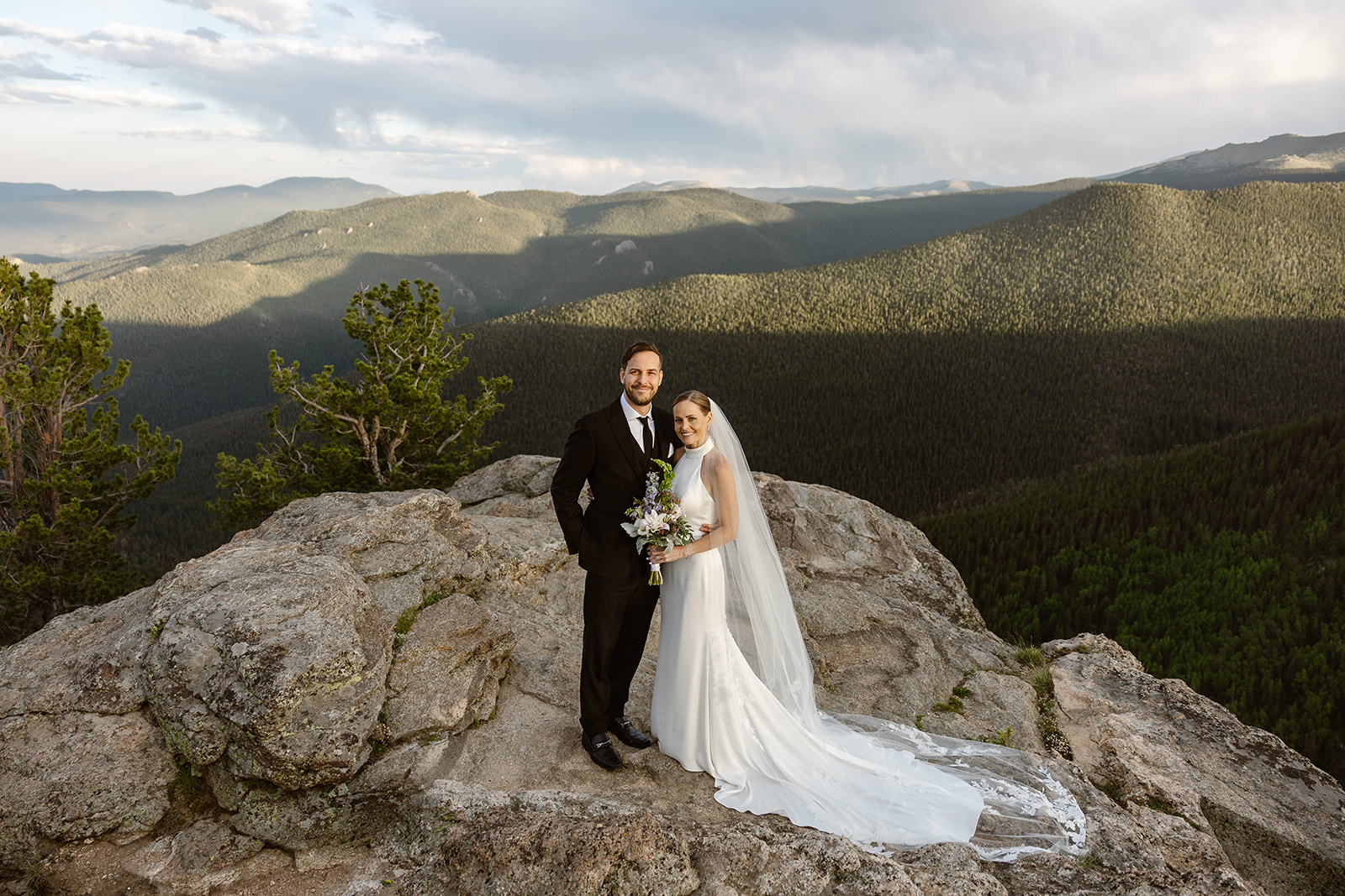 A newlywed couple smiling on top of a mountain along Squaw Pass in Idaho Springs, Colorado - one of the best places to elope in Colorado with a group of 10 or less!