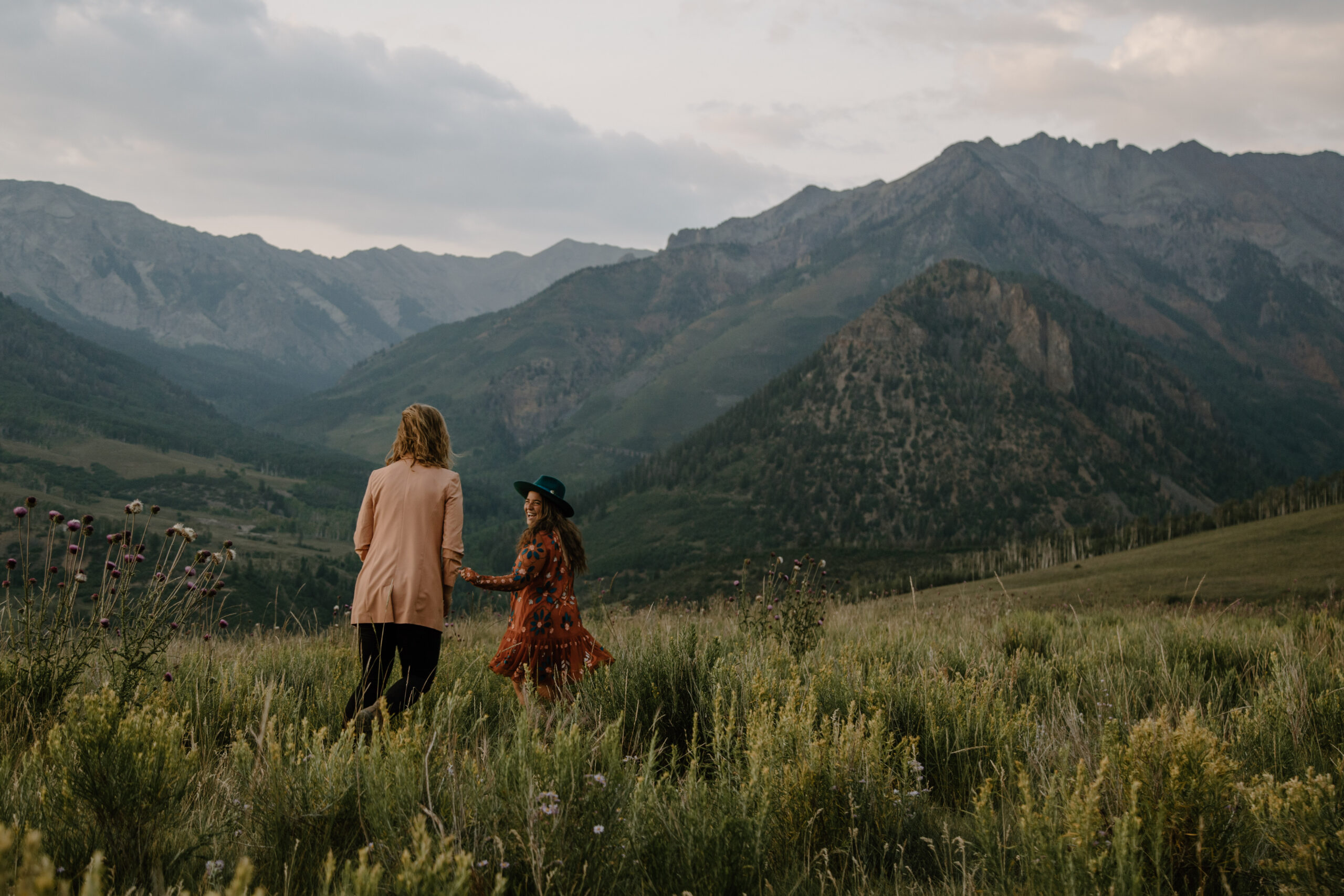 Two brides frolicking through a field of wildflowers in Telluride after a short elopement ceremony. 